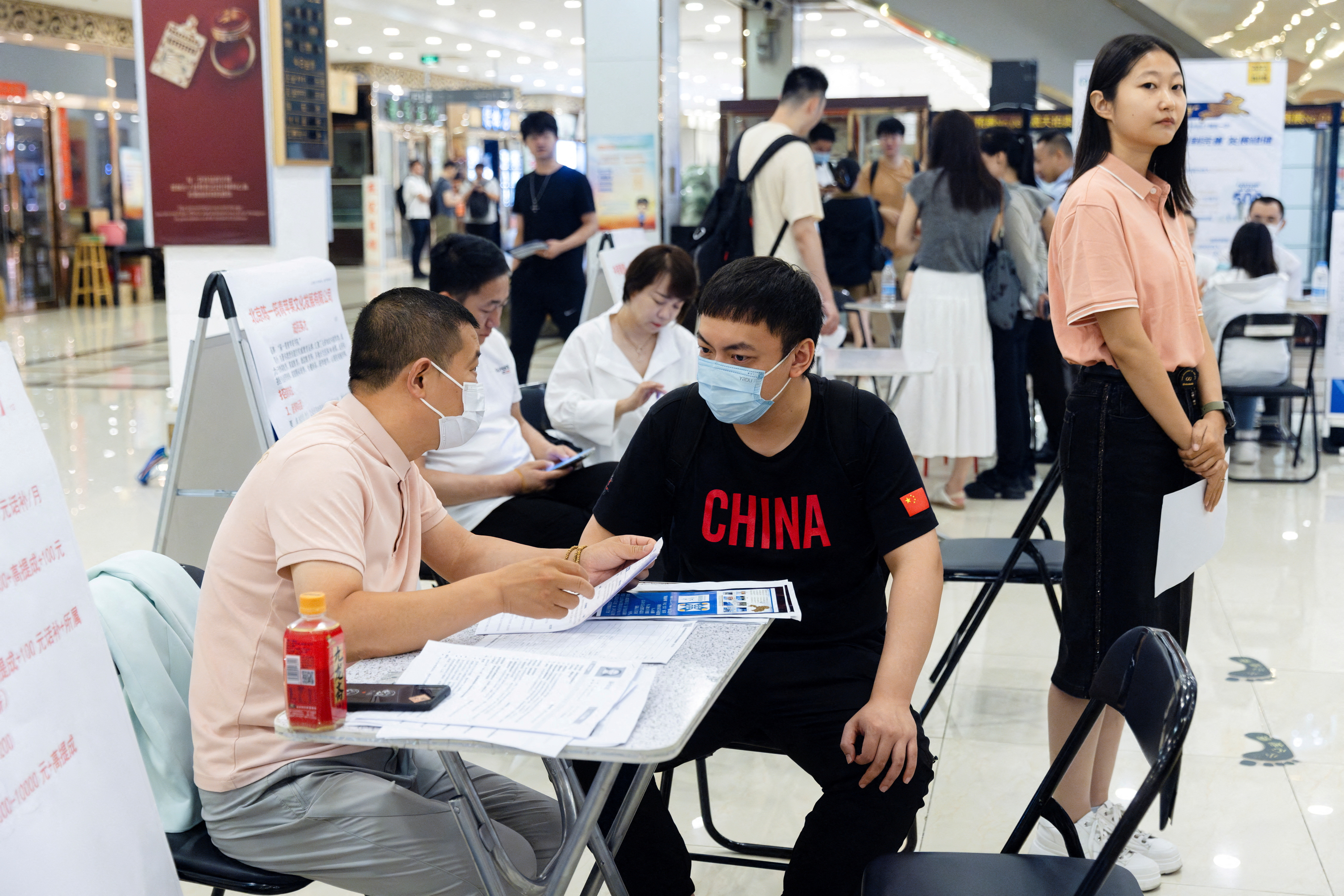 People attend a job fair in a mall in Beijing